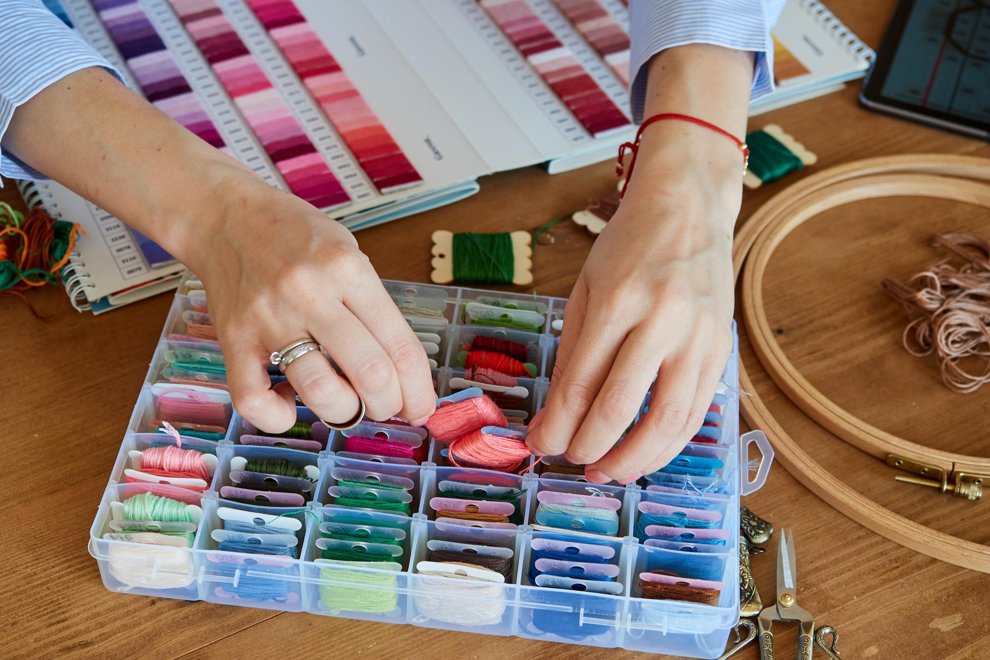 Artist arranging embroidered samples in studio